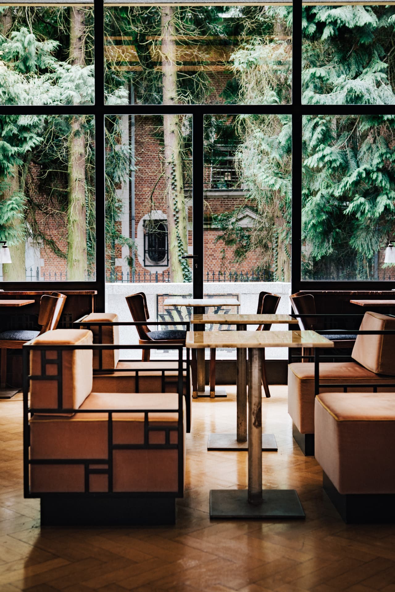 Refined restaurant interior with tall windows opening onto a green courtyard