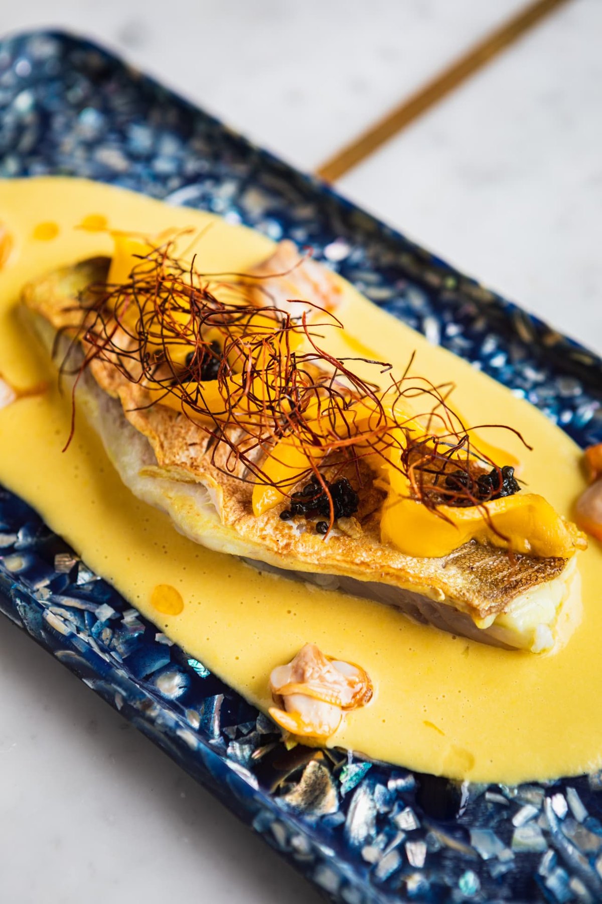 Sea bass in saffron velouté on a deep blue platter
