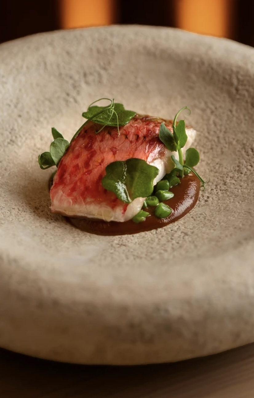 Red mullet with peas and pea shoots in a stone bowl