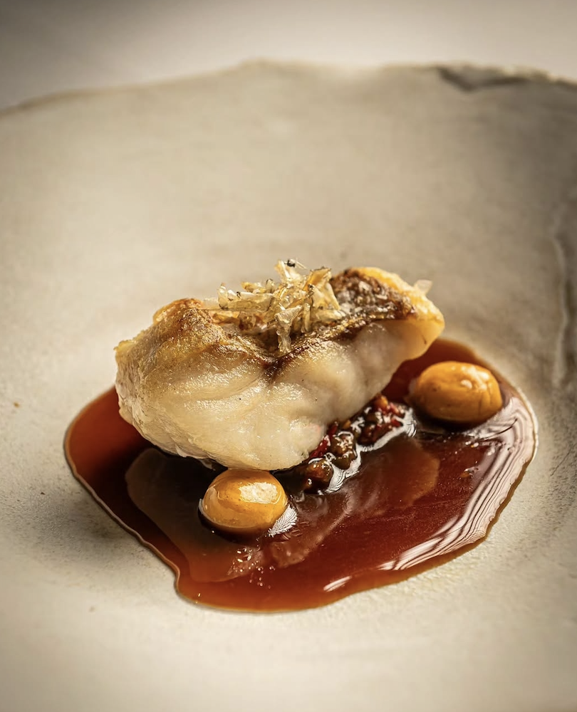 Crisp-skinned fish with glazed jus on a pale ceramic plate