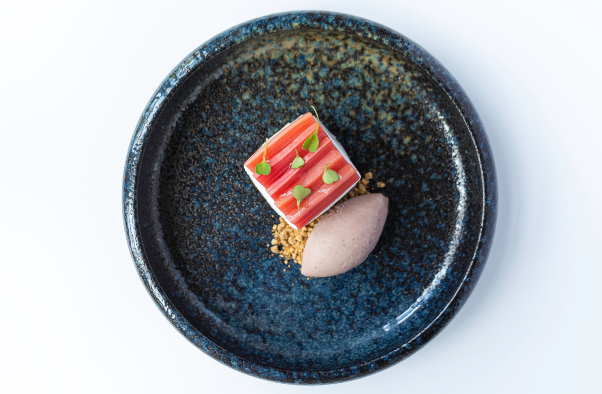 Rhubarb dessert with crumble and sorbet in a speckled blue bowl